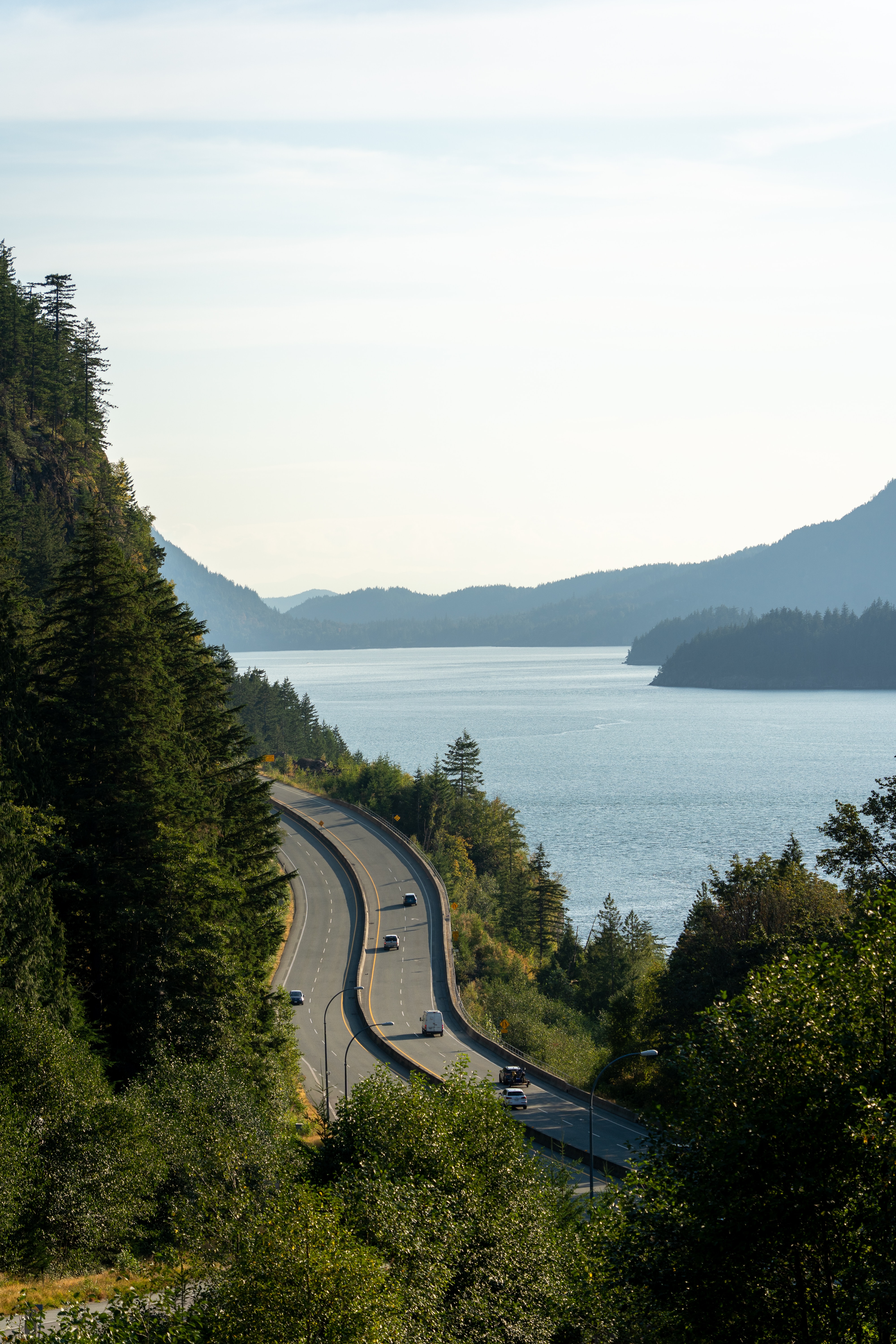 Image of cars travelling on a mountain highway beside a lake.